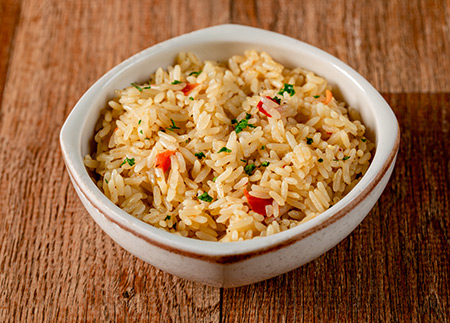 Arroz Pilaf em uma tigela branco em cima de uma mesa de madeira.