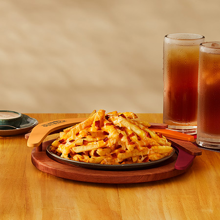 Batatas fritas com queijo e bacon servidas em um prato preto - Aussie Cheese Fries