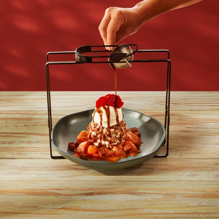 Sobremesa Cinnamon Oblivion em um prato branco sendo servida com calda de caramelo