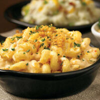 Pasta caracolina com creme de queijos e crumble de crouton em uma tigela preta - Aussie Mac N’ Cheese