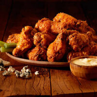 Outback Wings em um prato em cima de uma mesa de madeira.