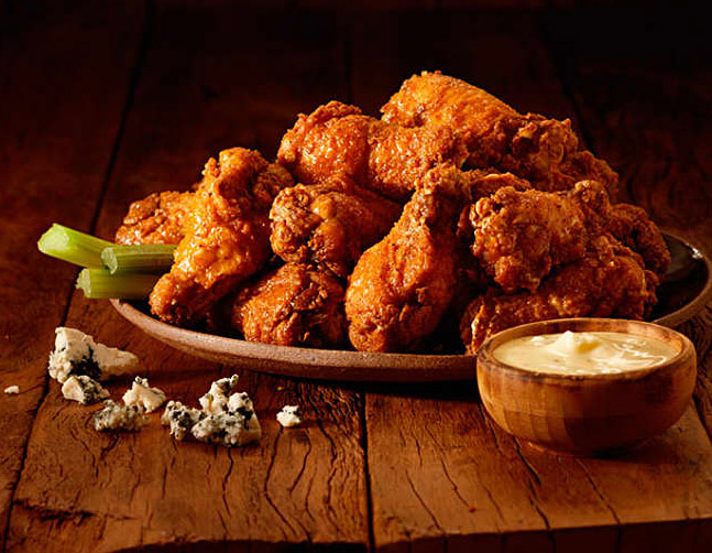 Outback Wings em um prato em cima de uma mesa de madeira.