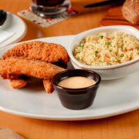Prato com peito de frango empanado, servido com molho honey mustard e arroz
