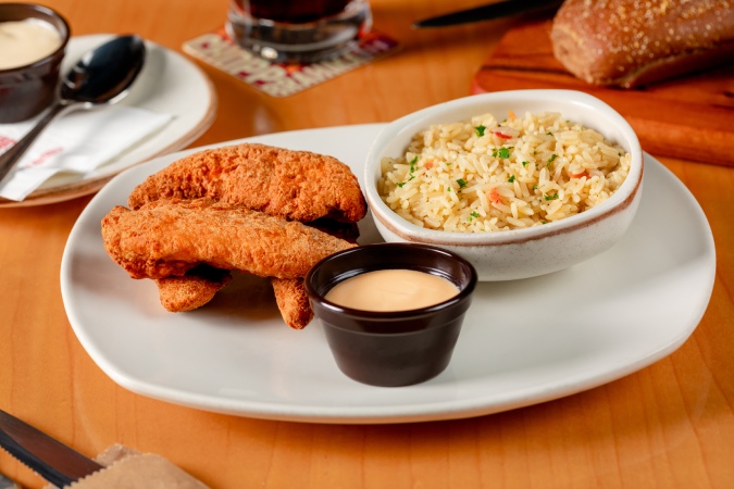 Prato com peito de frango empanado, servido com molho honey mustard e arroz