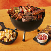 Churrasco com carnes, linguiça, costelas e espetos com legumes em uma mesa - Outback.