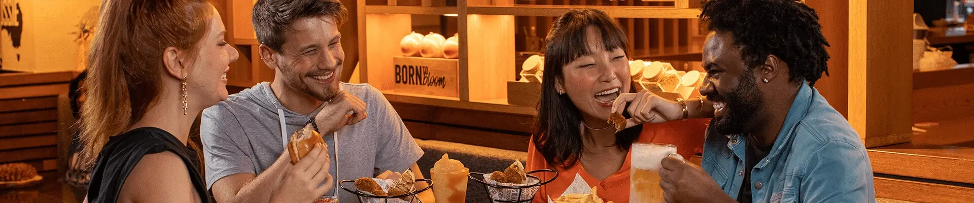 Um grupo de pessoas sentadas em uma mesa com comida e bebidas.