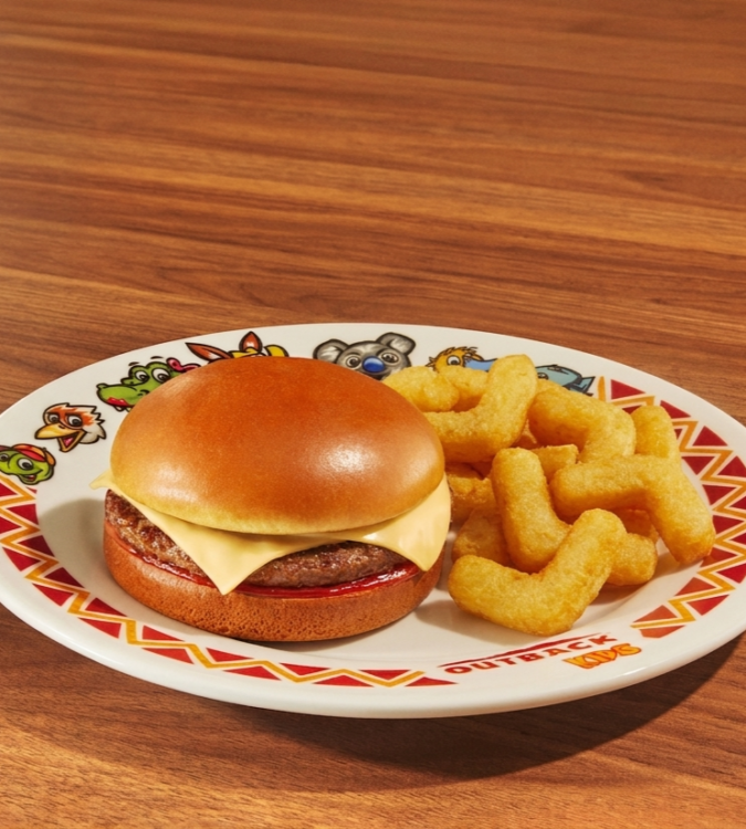 Cheeseburger com fritas boomerang, servido em prato decorado sobre uma mesa de madeira.