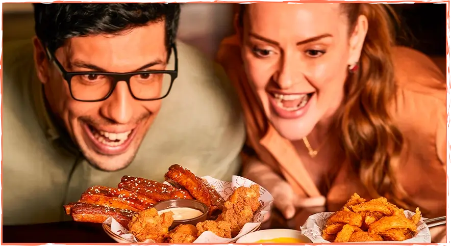 Homem e mulher animados olhando para os deliciosos pratos do Outback.